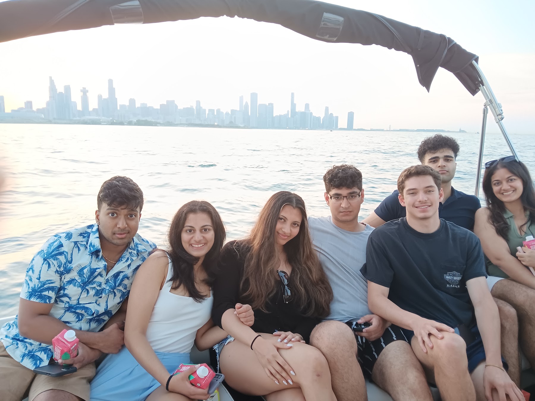 Six friends smiling together on the boat with the skyline in the distance