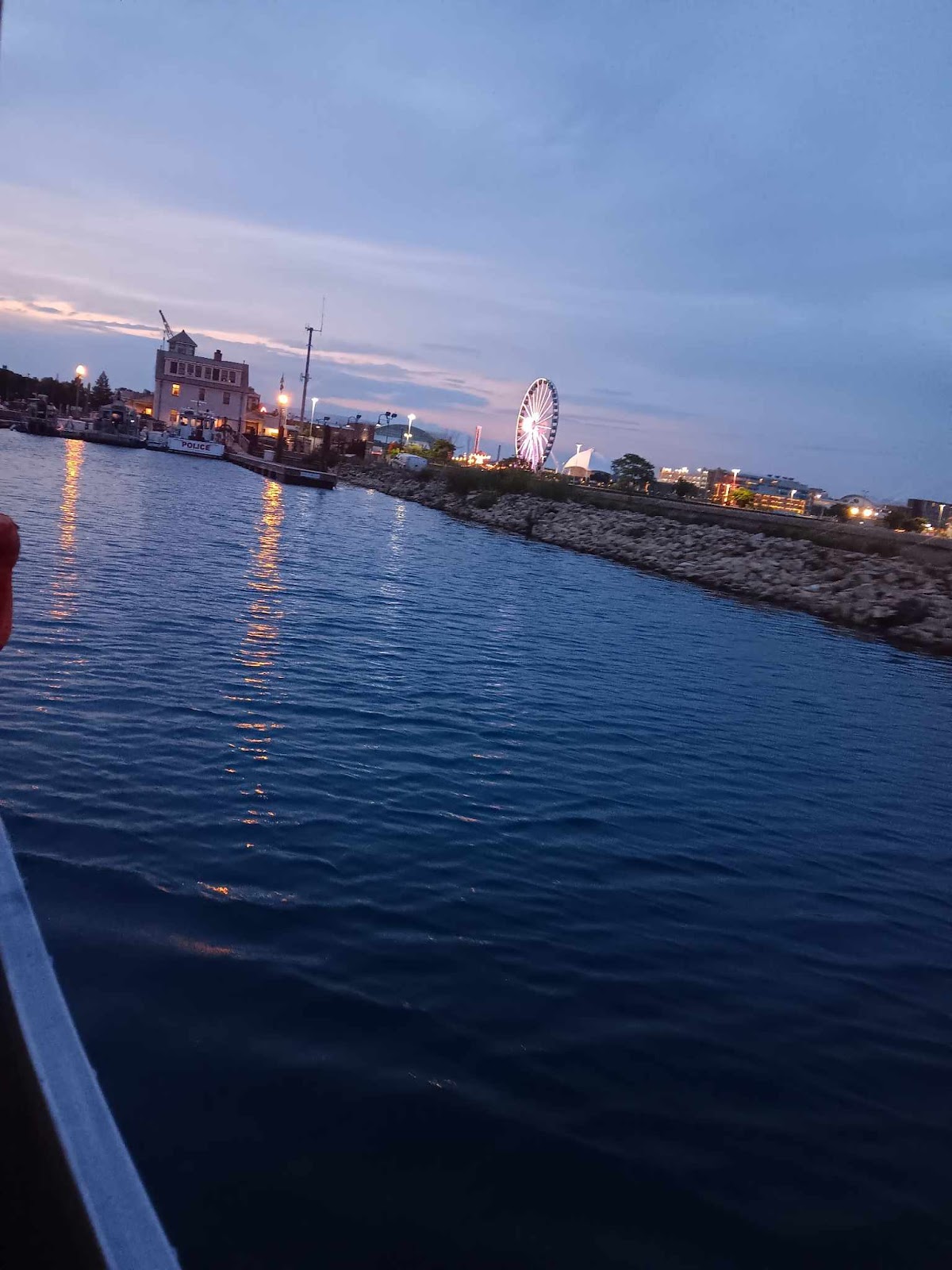 Calm harbor water at dusk with the lakefront lights coming on