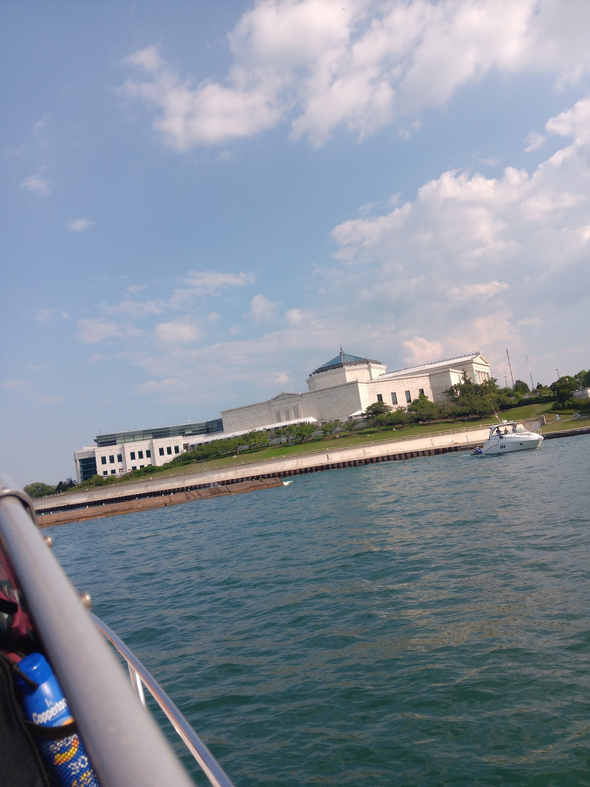 Green lake water and the Chicago lakefront under a cloudy blue sky