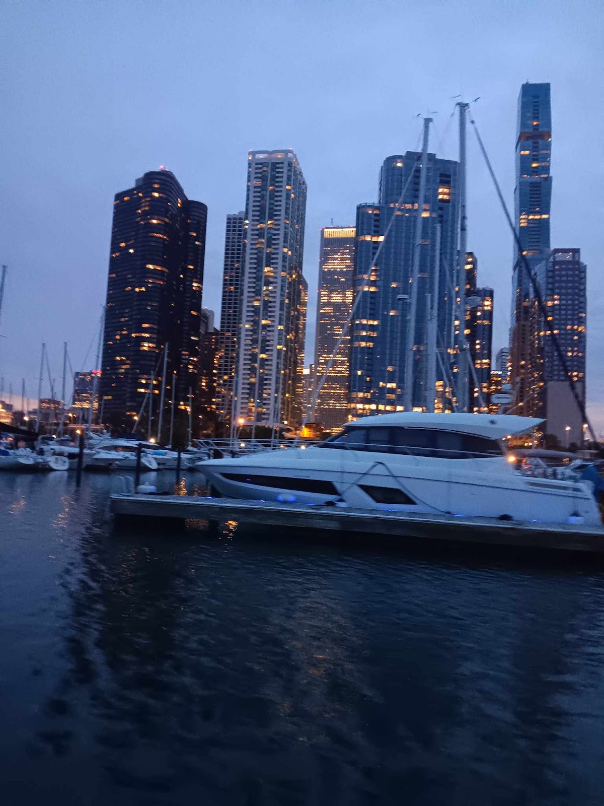Downtown towers at dusk behind a yacht moored in the harbor